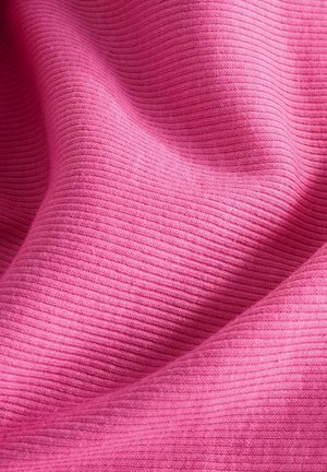 Närbild av rosa ribbad tyg med mjuka veck och synlig stickad struktur.