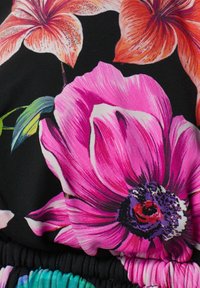 Tyg med blommönster som har stora rosa och orange blommor på en svart bakgrund, med detaljer av elastisk midja och livliga färger.