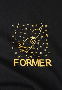 Tejido negro con un gráfico amarillo de un pájaro rodeado de estrellas, con la palabra "FORMER" debajo en texto oscuro y estilizado.