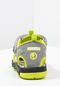 Gray and neon green sandal with a textured upper, adjustable strap, and patterned outsole. Features a prominent logo and sturdy heel support.