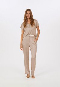 Beige satin top and matching pants with a relaxed fit. Top features a V-neckline and soft texture, while pants have an elastic waistband.