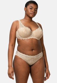 Beige pitsimalliset alusvaatteet, joissa on rintaliivit, joissa on aaltoilevat reunat, ja yhteensopivat hipster-housut, molemmat kukkakuosiset ja pehmeät.