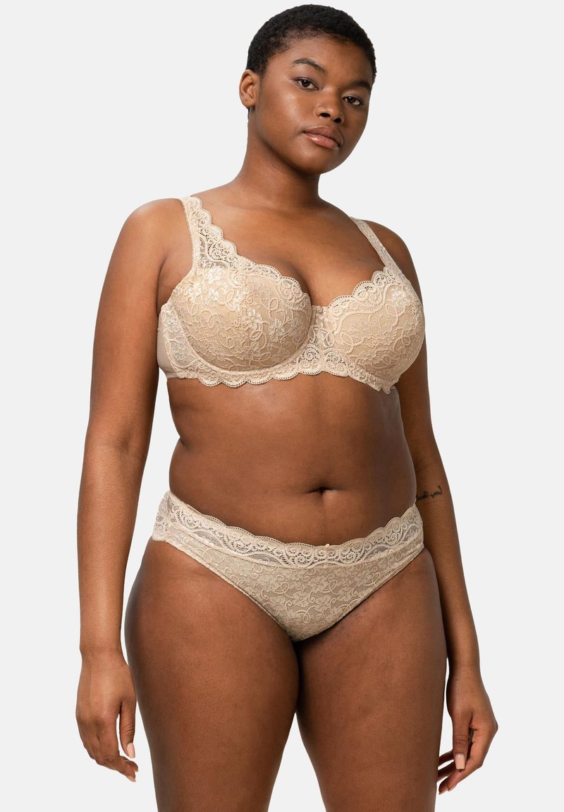 Beige pitsimalliset alusvaatteet, joissa on rintaliivit, joissa on aaltoilevat reunat, ja yhteensopivat hipster-housut, molemmat kukkakuosiset ja pehmeät.