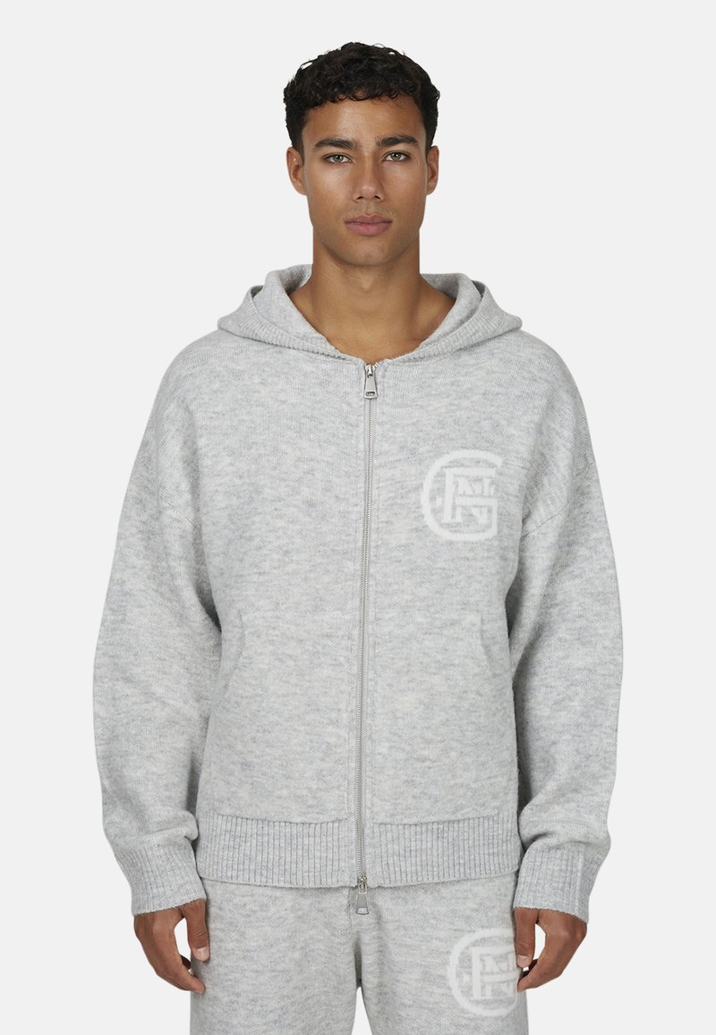 Szara rozpinana bluza z kapturem wykonana z miękkiego materiału, wyposażona w przednią kieszeń, ściągacze na rękawach oraz logo nadrukowane na lewej piersi.