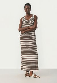 Raitapuku maksimekko ruskeassa ja beessissä, jossa on kauluskdesign ja hihaton muotoilu. Silkkinen kangas, rento leikkaus ja sivuaukot.