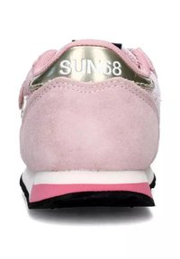 Sneaker in suede rosa con marchio metallico argento sul tallone, suola media bianca, accenti rosa e suola nera. Parte superiore testurizzata con punta rotonda.