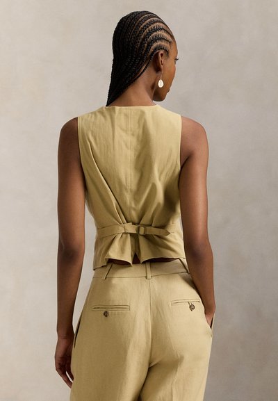 Χακί αμάνικη μπλούζα με δέσιμο στην πλάτη, ραμμένη γραμμή και υφασμάτινη υφή. Συνδυασμένη με αντίστοιχο ψηλόμεσο παντελόνι με τσέπη.