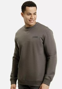 Szara bluza z okrągłym dekoltem, długimi rękawami i subtelną naszywką z logo na piersi. Materiał wydaje się miękki i teksturowany.