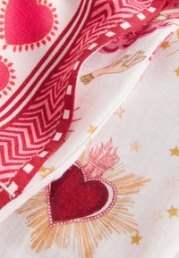 Tela con patrón estratificado en rojo y blanco que muestra corazones rojos, destellos dorados y un brazo ilustrado que sostiene una rosa.