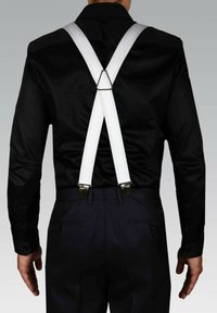 Bretelles élastiques blanches avec des clips en métal, portées sur une chemise noire. L'arrière présente un connecteur triangulaire et des textures lisses.