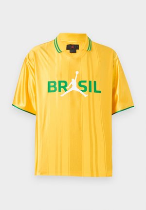 Κίτρινο αθλητικό πόλο με κοντά μανίκια και πράσινη επένδυση στο γιακά και στα μανίκια, κείμενο "BRASIL" και λευκό σιλουέτα παίκτη μπάσκετ μπροστά.
