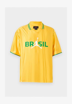 Κίτρινο αθλητικό πόλο με κοντά μανίκια και πράσινη επένδυση στο γιακά και στα μανίκια, κείμενο "BRASIL" και λευκό σιλουέτα παίκτη μπάσκετ μπροστά.