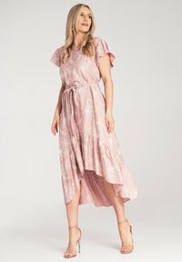 Różowa maxi sukienka w kwiaty z krótkimi falbaniastymi rękawami, związaną w talii i asymetrycznym dołem. Wykonana z lekkiego materiału z teksturowanymi wzorami.