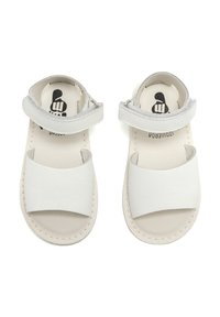 Sandalias de cuero blanco con una tira ancha en la parte delantera, correa ajustable en el tobillo y una plantilla acolchada en color beige con detalle de costura.