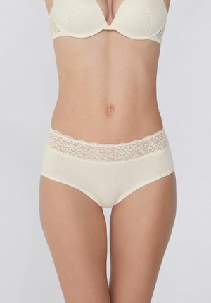 Culotte haute beige bordée de dentelle, fabriquée en tissu doux avec une texture lisse et des détails côtelés sur le corps.