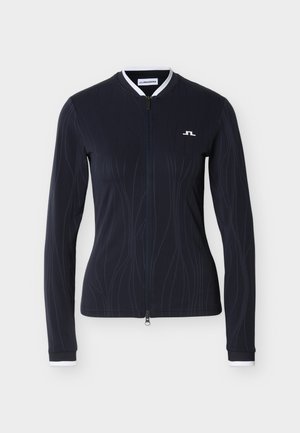Veste de sport bleu marine à manches longues avec fermeture éclair frontale, design ondulé texturé, col et poignets blancs. Présente un petit logo sur la poitrine.