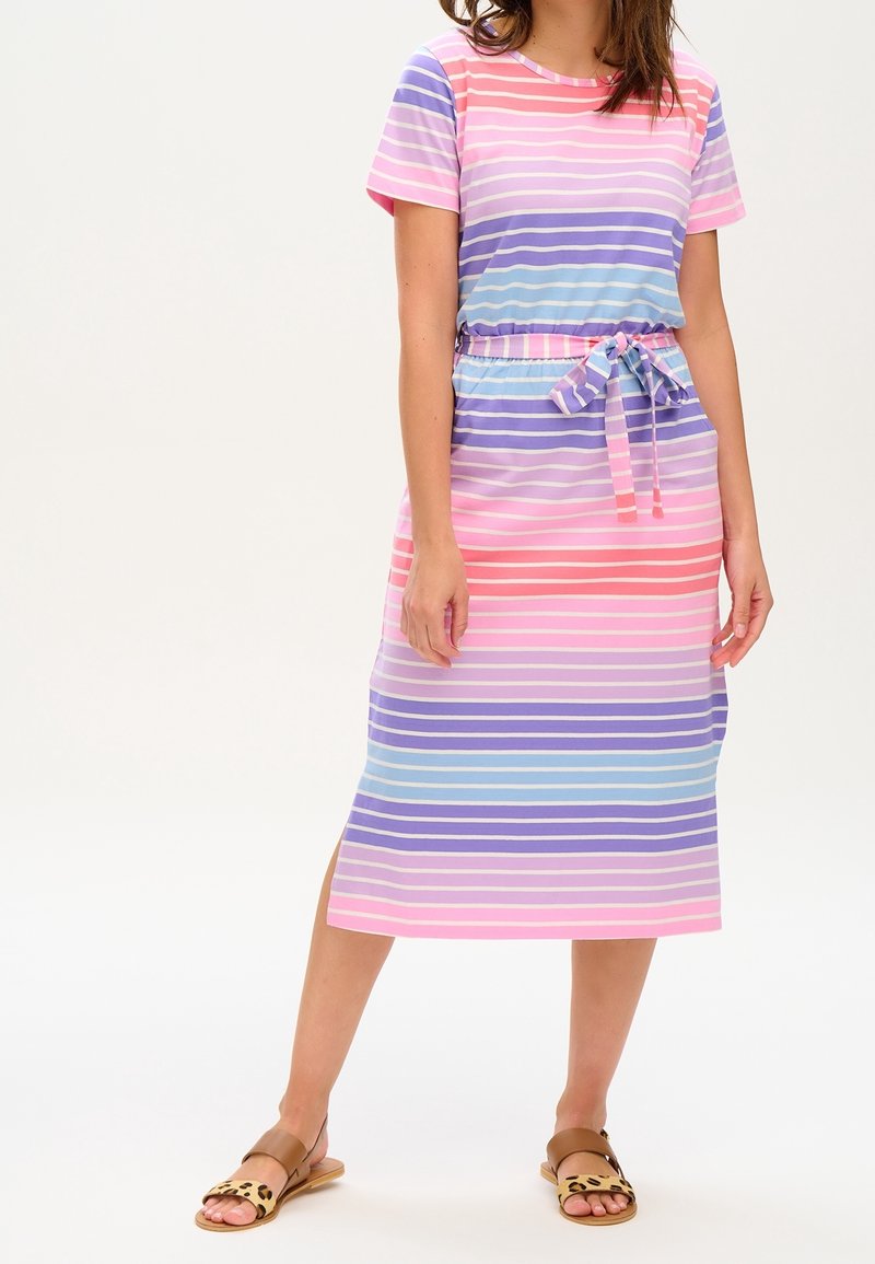 Femme portant une robe midi à rayures pastel avec manches courtes et lien à la taille, associée à des sandales plates marron à brides imprimé léopard.