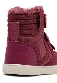 Wysokie bordowe trampki z teksturowanej tkaniny i akcentami z gumy, z puszystym kołnierzem, zapięciem na rzep oraz kontrastującymi czarnymi detalami.