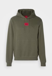Sweat à capuche vert olive avec poche kangourou avant et écusson logo carré rouge portant la mention HUGO centré sous l'encolure.