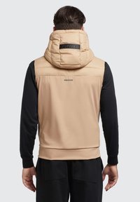 Beige puffertakó, magas gallérral és logóval a hátulján, fekete hosszú ujjak, sima felülettel. Texturált anyag és varrás nélküli kivitel.