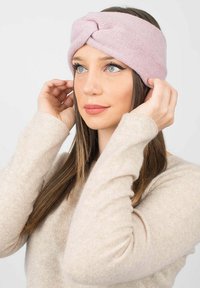 Fascia per capelli lavorata a maglia rosa con design a spirale, texture morbida e banda di tessuto ampia, indossata da un modello con capelli lunghi.
