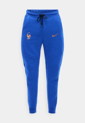 Kék athletikus edzőnadrág fekete húzózsinórral, narancssárga Nike logóval és a Francia Labdarúgó Szövetség kakas emblémájával, amely két csillagot tartalmaz.