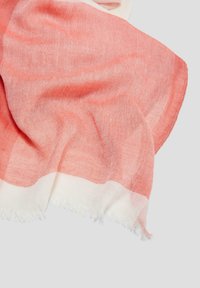Écharpe dégradé corail et blanc en tissu doux et texturé ; présente des bords frangés et un design léger et fluide.