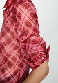 Camicia trasparente a quadri rossi e rosa, maniche lunghe arrotolate, con dettaglio a bottoni sui polsi, in un morbido tessuto.