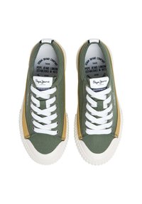 Plátěné tenisky v olivově zelené barvě s hořčicovými akcenty, bílými tkaničkami a gumovými podrážkami. Obsahují detaily loga na jazyku a vnitřní podšívce.