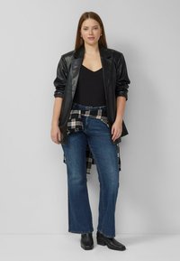 Czarna skórzana marynarka na czarnej bluzce, niebieskie rozkloszowane jeansy, koszula w kratę zawiązana w talii, czarne botki, styl casual.