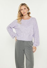 Maglione lavorato a maglia lavanda con scollatura a onda, maniche larghe con dettagli in pizzo, abbinato a pantaloni palazzo grigi.
