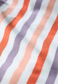 Randigt tyg med växlande vågiga linjer i orange, ljusrosa, ljuslila och vit. Mjuk textur med en slät yta.