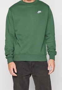 Grön sweatshirt i mjukt material med rund halsringning och ribbade ärmmuddar. Litet vitt Nike-logotyp på vänstra bröstet.