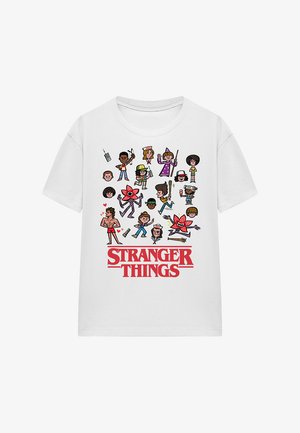 White cotton t-shirt featuring various cartoon characters from "Stranger Things" printed in colorful detail above the text "STRANGER THINGS" in red.