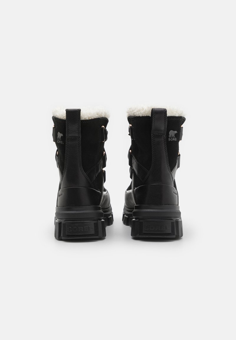 Czarne wodoodporne botki za kostkę z białym sztucznym futrem, wykonane z mieszanki zamszu i skóry, z regulowanymi paskami i wytrzymałymi gumowymi podeszwami.