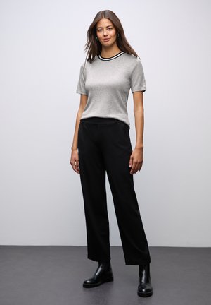 Szara koszulka z krótkim rękawem, z czarnym ściągaczem przy dekolcie, zestawiona z wysokim stanem czarnymi spodniami i czarnymi botkami za kostkę na neutralnym tle.