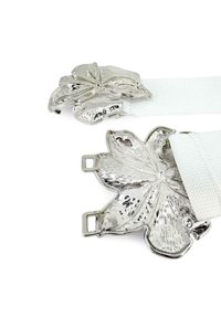 Fibbia a forma di foglia in argento su una cintura elastica bianca, caratterizzata da una superficie texturizzata e dettagliate venature delle foglie. Finitura liscia con due clip di attacco.