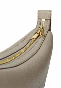 Beige lædertaske med en tekstureret overflade, der har en guldfarvet lynlås og metaldele; veldefineret form med afrundede kanter og en bred åbning.