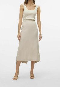 Beige, knielanger Rock kombiniert mit einem leichten, gerippten Tanktop. Der Rock hat eine glatte Textur, während das Top einen quadratischen Ausschnitt und eine zarte Bordüre aufweist.