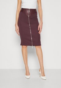 Violette Bodycon-Rock mit einem strukturierten Taillenbund aus Kunstleder und einem zentralen silbernen Reißverschluss. Glatte Textur und knielanges Design.