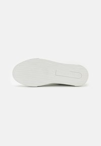 Tenis alb cu o talpă din cauciuc texturat. Înglobează un logo imprimat și o ușoară curbură la vârf. Material superior neted pentru confort.