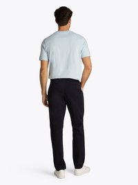 T-shirt de algodão azul claro com mangas curtas, combinada com calças chino azul-marinho e ténis brancos. Design simples, vista traseira sem adornos.