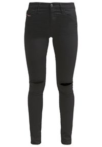 Vaqueros pitillo negros hechos de mezclilla, con una textura suave y dos desgarraduras en las rodillas. Diseño clásico de cinco bolsillos con cierre de botón.