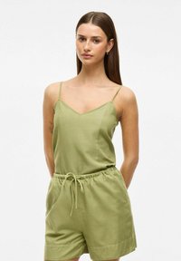 Olivengrøn, ærmeløs jumpsuit med V-udskæring, der har en elastisk talje og lommer. Fremstillet af blødt, letvægtsstof.