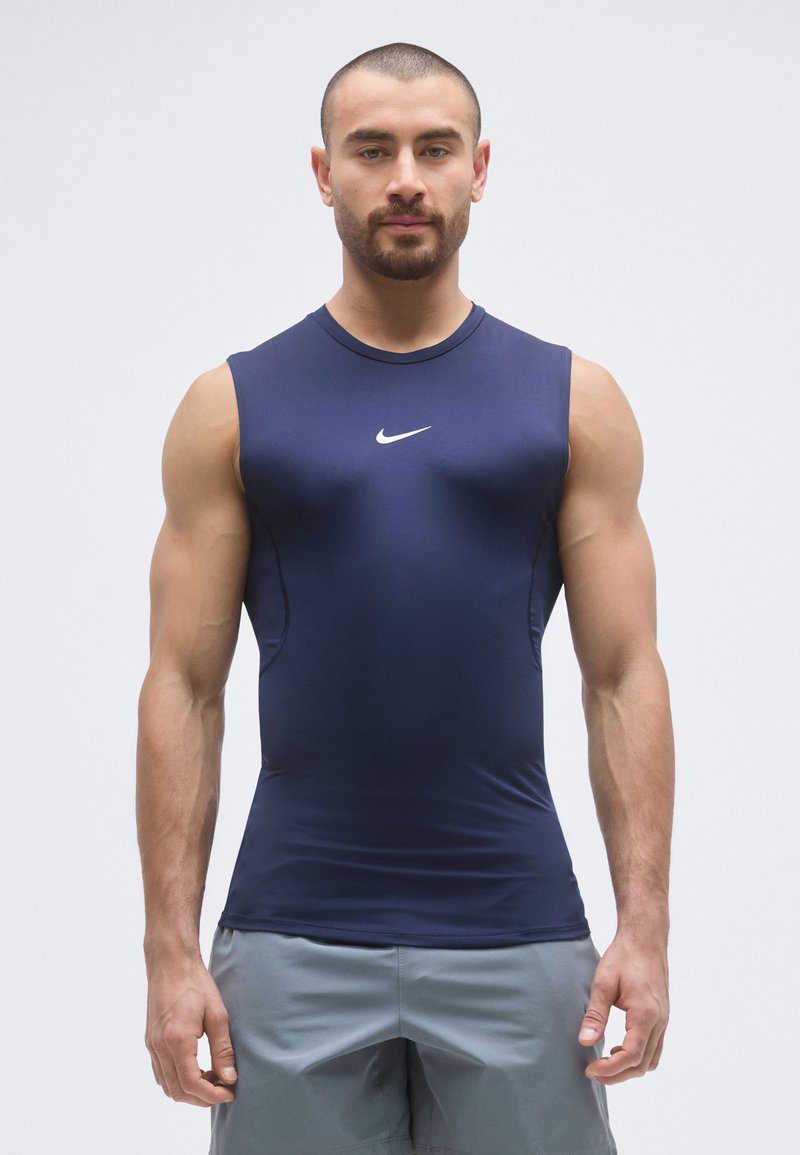 Top atletico senza maniche color blu navy con design aderente. Presenta un logo Nike bianco sul petto e cuciture a contrasto lungo i lati.