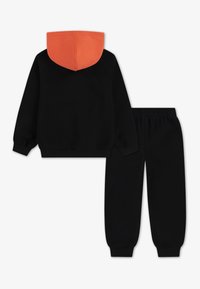 Sweatshirt preto com capuz forrado a laranja e calças de fato pretas. Textura suave, punhos e cós canelados. Conjunto casual de duas peças.