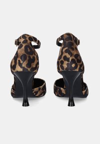 Zapatos de tacón alto con estampado de leopardo, con una suave textura de ante, tacón negro y detalle de correa en el tobillo. Cuentan con punta abierta y diseño de parte trasera redondeada.