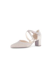 Scarpa con tacco alto beige luccicante, punta affilata, design con cinturino incrociato e tacco blocco. La tomaia presenta una finitura testurizzata e scintillante.