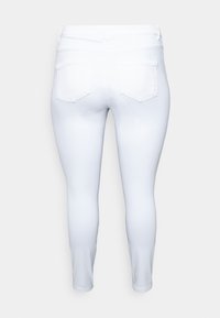 Jean skinny blanc avec une taille haute, texture lisse et poches arrière avec un détail de couture simple.