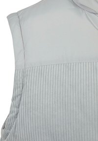 Lichtgrijs mouwloos kledingstuk met een gewatteerd bovenstuk en een geribbelde gebreide onderkant, waarbij de details van de schouders en armsgaten zichtbaar zijn.